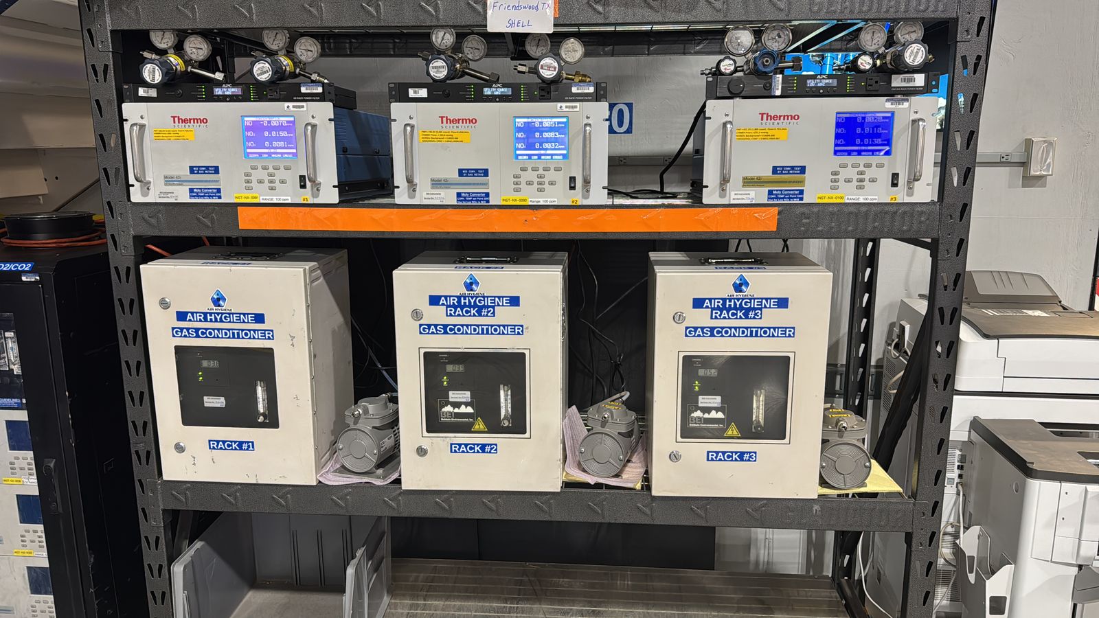 Three sample gas conditioner units lined up on a warehouse shelf, front panels labelled Gas Conditioner
