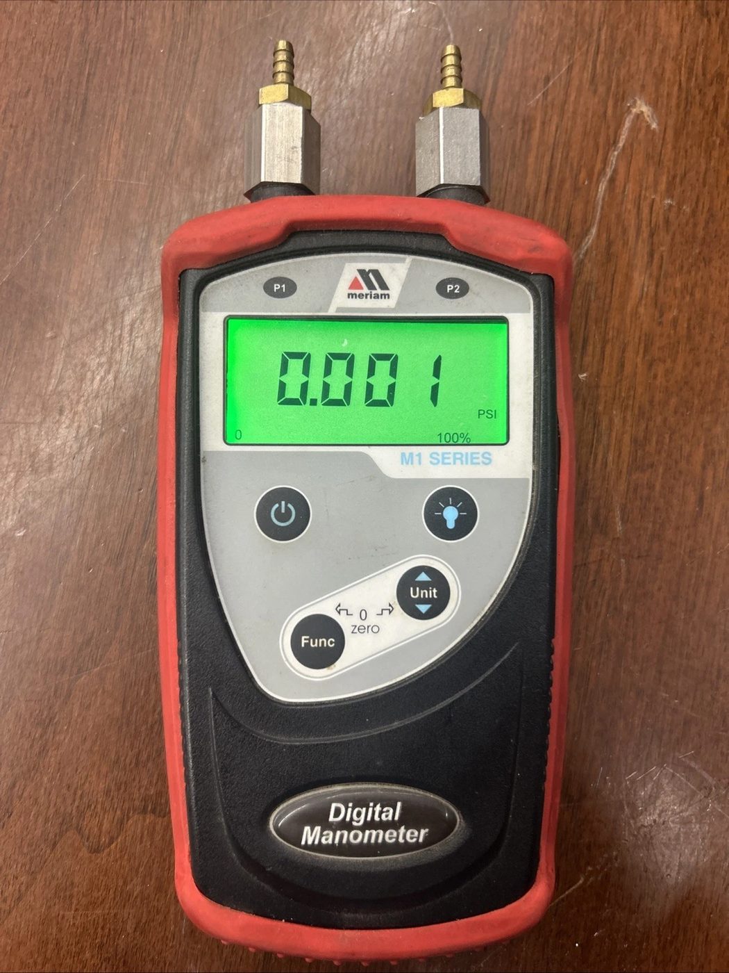 A Meriam M1 Series digital manometer in a red protective boot, its green display reading 0.001