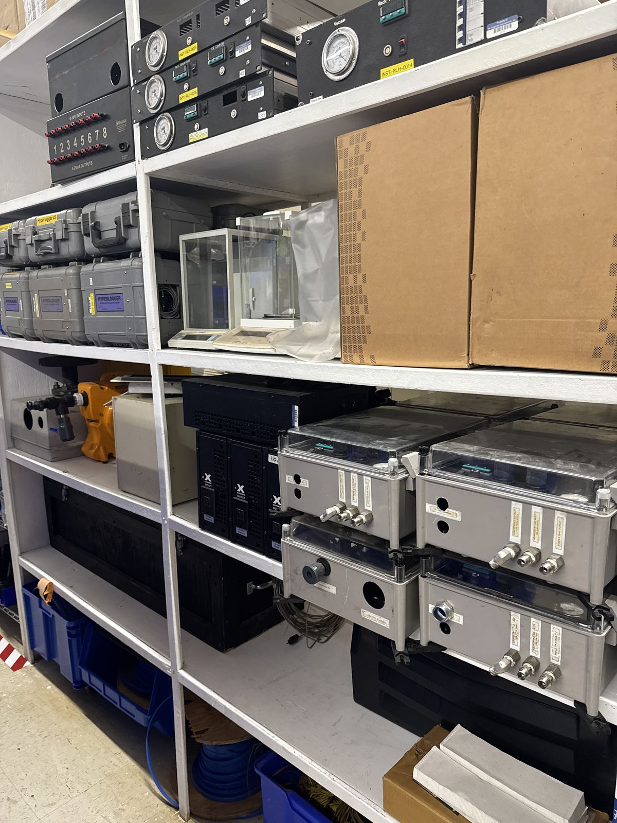 Warehouse shelving holding analyzers, instrument cases and boxed spares